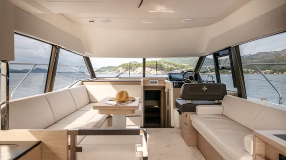 Spacious luxury yacht interior salon with dining table, comfortable lounge seating, and panoramic sea views of the Croatian coast.