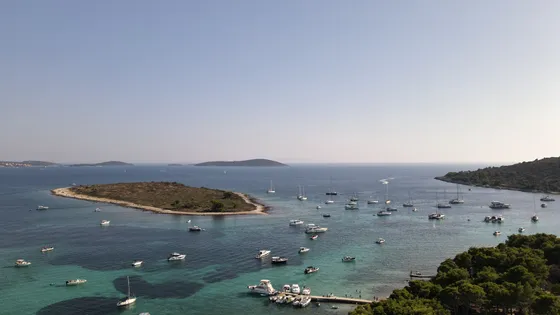 Aerial view of Dalmatian Blue Lagoon near Split with crystal-clear waters, a small island, and numerous boats.