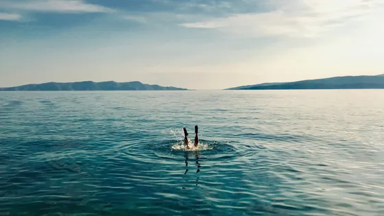 Person diving into the clear turquoise Adriatic Sea with distant islands, showcasing a refreshing private boat tour experience in Croatia.
