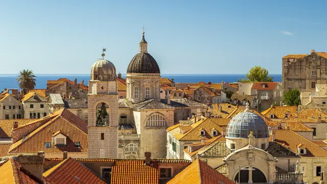 Panoramic aerial view of Dubrovnik Old Town terracotta rooftops, cathedral dome and blue Adriatic Sea, Croatia