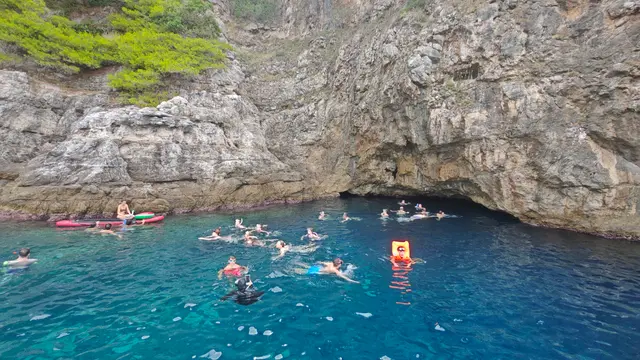 People swimming and snorkeling in the vibrant blue water of a cave near Dubrovnik, Croatia, during a private boat tour.
