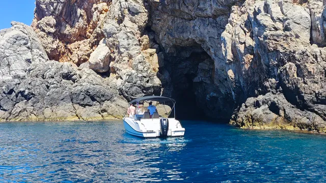 A luxury private boat tour exploring a secluded rocky cove with clear blue waters and lush green cliffs near Dubrovnik.
