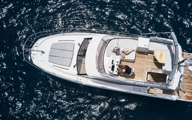 Aerial view of a luxury yacht from our fleet sailing in crystal-clear blue waters, featuring multiple decks, spacious lounging areas, and a sleek white exterior.