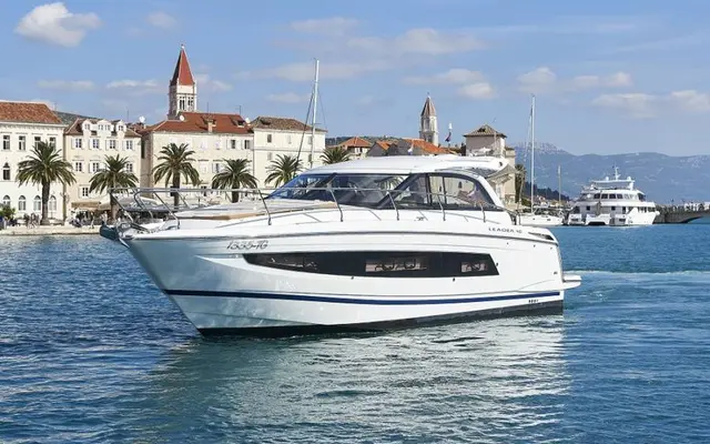 Luxury yacht cruising along Dubrovnik's picturesque coastline, with historic architecture and palm trees in the background