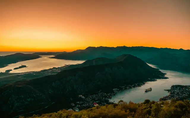 Sunset panoramic view over the Bay of Kotor seen from the Lovćen mountain road, with the fjord-like inlet glowing orange