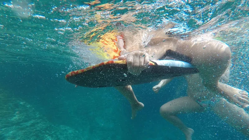 Underwater view of snorkeler exploring crystal-clear turquoise waters, surrounded by sunlight and bubbles.