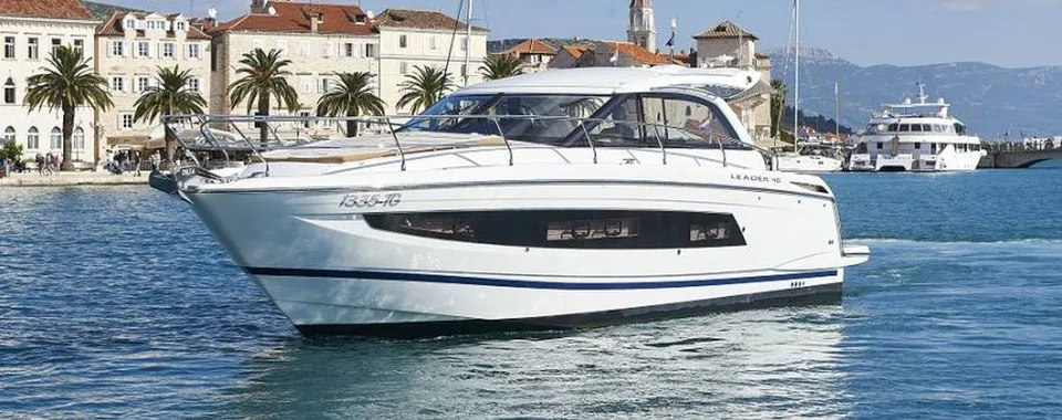 Luxury yacht cruising along Dubrovnik's picturesque coastline, with historic architecture and palm trees in the background
