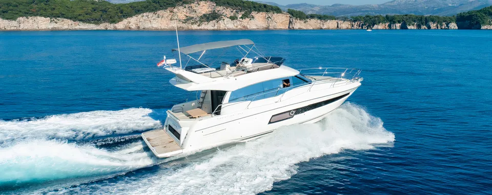 Luxury yacht from our fleet cruising through crystal-clear blue waters near Dubrovnik on a sunny day.