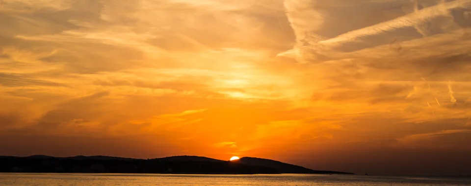 Golden sunset over Dubrovnik old town walls and Adriatic Sea viewed from hilltop trail
