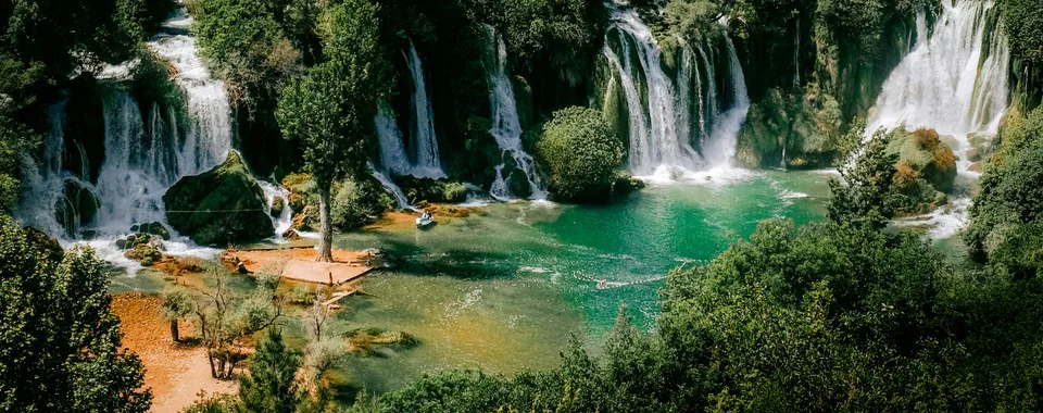 Turquoise swimming pool beneath Kravice Waterfalls on a sunny summer day in Bosnia and Herzegovina