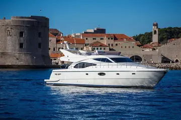 Luxury yacht sailing past Dubrovnik old town walls, Croatia.