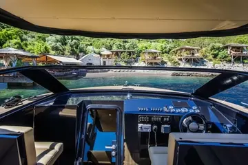 Luxury yacht cockpit view of serene coastal resort with bungalows & clear water, perfect for luxury Dubrovnik escape to islands.