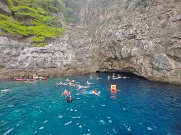 People swimming and snorkeling in the vibrant blue water of a cave near Dubrovnik, Croatia, during a private boat tour.