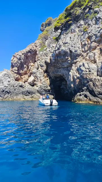 Luxury speedboat approaching a natural cave entrance on the clear blue Adriatic Sea near Dubrovnik, Croatia.