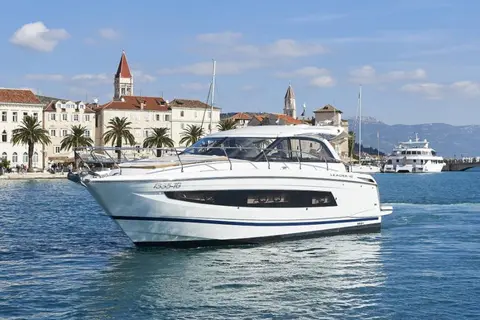 Luxury yacht cruising along Dubrovnik's picturesque coastline, with historic architecture and palm trees in the background