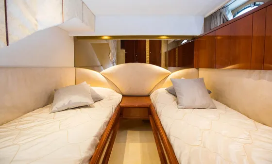Luxurious yacht cabin with twin beds, plush pillows, and warm lighting. Elegant wood finishes and cozy atmosphere for Elafiti Islands cruise.