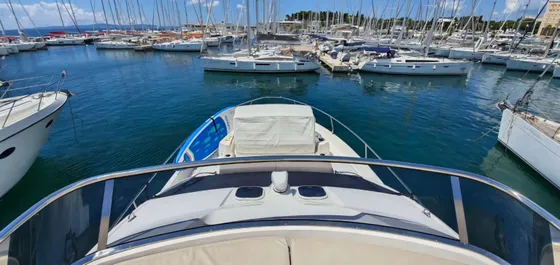View from a motorboat in a vibrant Dubrovnik Frapa marina, packed with numerous sailing yachts and other vessels, under a clear blue sky.