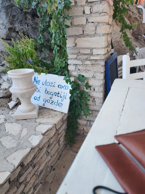 Charming Dubrovnik detail: White stone planter with handwritten sign in Croatian, green ivy, and rustic wall texture