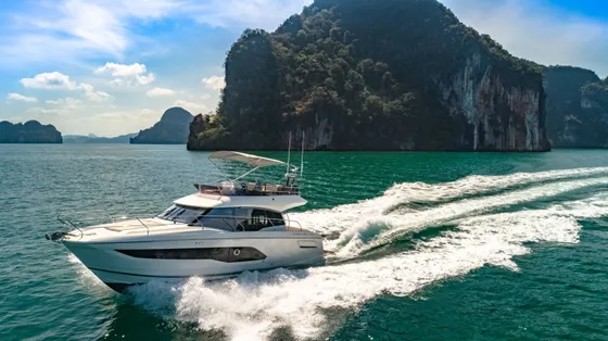 Luxury Prestige Yacht cruising through turquoise waters near lush coastal cliffs