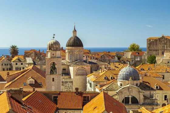 Panoramic aerial view of Dubrovnik Old Town terracotta rooftops, cathedral dome and blue Adriatic Sea, Croatia