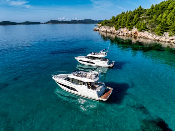 Luxury yacht charter in Croatia. Two Prestige 420 Tendo motor yachts on clear blue Adriatic Sea near Dubrovnik coastline.