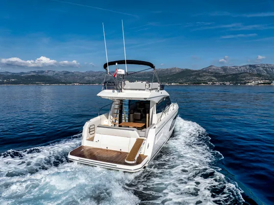 Luxury yacht cruising crystal blue Adriatic waters near Dubrovnik, Croatia, with stunning mountain backdrop under a clear sky.