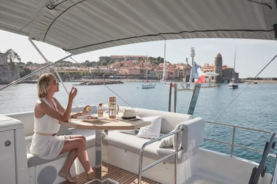 Woman enjoying a refreshing drink on a luxury yacht deck, overlooking a picturesque Dubrovnik coastal town and shimmering Adriatic Sea.