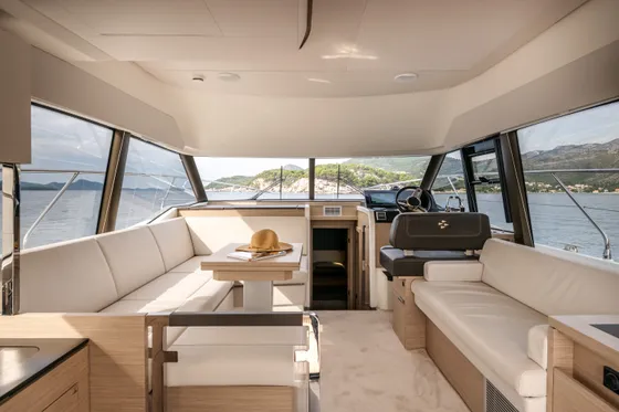 Spacious luxury yacht interior salon with dining table, comfortable lounge seating, and panoramic sea views of the Croatian coast.