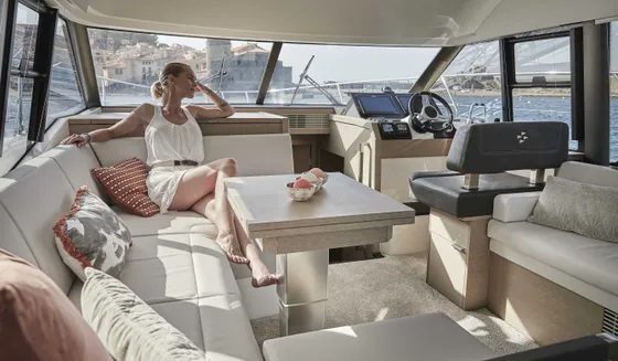 Luxury yacht interior with woman relaxing on a sofa, panoramic view of Dubrovnik. Prestige 420 charter in Croatia.