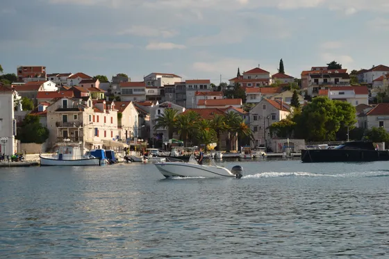 A white luxury boat sails past the picturesque Maslinica harbor on Šolta island, Croatia.