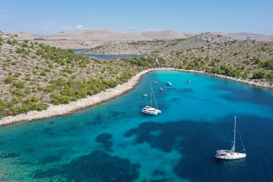 Aerial view of a catamaran and sailboats anchored in Croatia's Blue Lagoon, featuring incredibly clear turquoise water and lush islands, ideal for a private boat tour from Split.