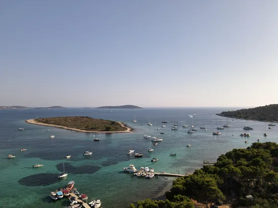 Aerial view of Dalmatian Blue Lagoon near Split with crystal-clear waters, a small island, and numerous boats.