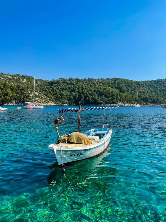 White private boat on crystal-clear Adriatic Sea, showing visible seabed and lush Dalmatian coast for Split island hopping.