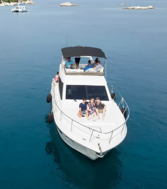 Aerial view of a luxury yacht charter cruising the crystal-clear turquoise waters of the Dubrovnik Elaphite Islands. A small group of friends or family enjoys a private boat tour, surrounded by stunning islands, perfect for an exclusive island hopping adventure or premium Dubrovnik vacation.