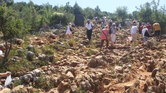 Pilgrims climbing the rocky path up Apparition Hill in Medjugorje, Bosnia and Herzegovina