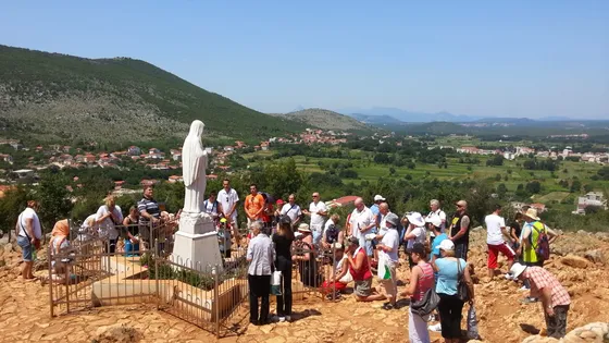 St. James Church in Medjugorje with twin bell towers and clock faces against a clear blue sky
