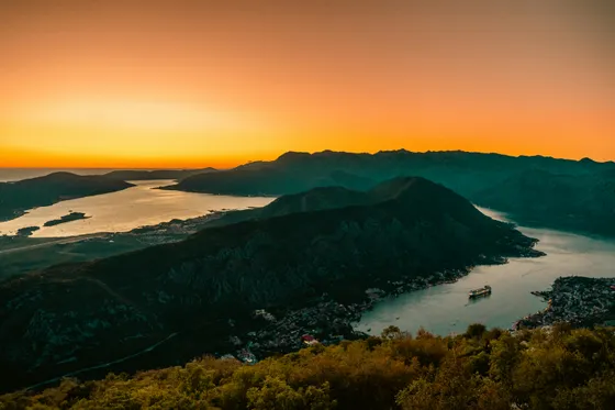 Sunset panoramic view over the Bay of Kotor seen from the Lovćen mountain road, with the fjord-like inlet glowing orange