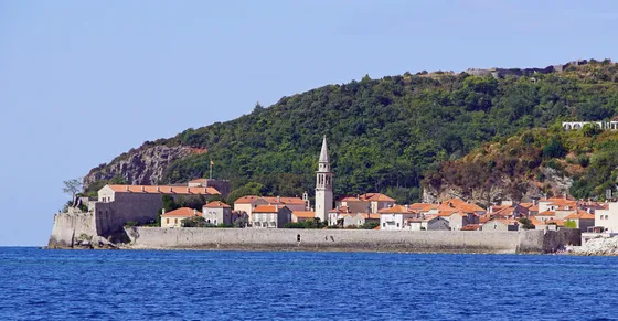Budva Old Town seen from the sea — medieval Venetian walls, terracotta rooftops and the bell tower of Saint Ivan, Montenegrin Adriatic coast