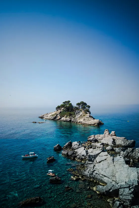 Katič island off Petrovac na Moru with small fishing boats in the clear blue Adriatic, southern Montenegro