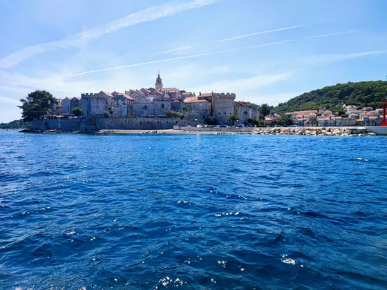 View of the walled town of Korcula from the sea, showcasing its historic architecture and beautiful waterfront.