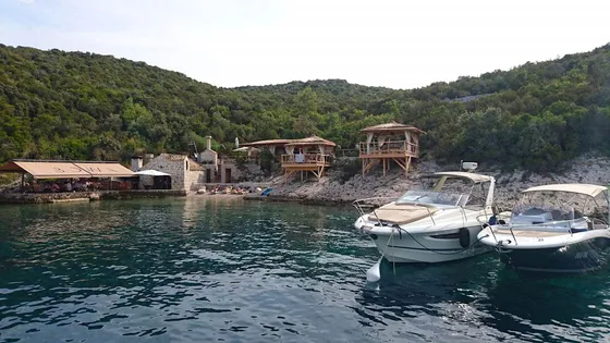 Secluded coastal cove with rustic buildings and moored boats, surrounded by lush green hills - a hidden gem near Dubrovnik, BOWA restaurant