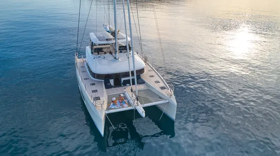 Aerial view of Lagoon 65 Amada Mia luxury catamaran charter in Croatia at sunset, with guests relaxing on the bow.