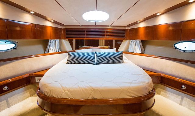 Luxury yacht interior: Spacious cabin with comfortable bed, wooden finishes, and ambient lighting for ultimate relaxation at sea