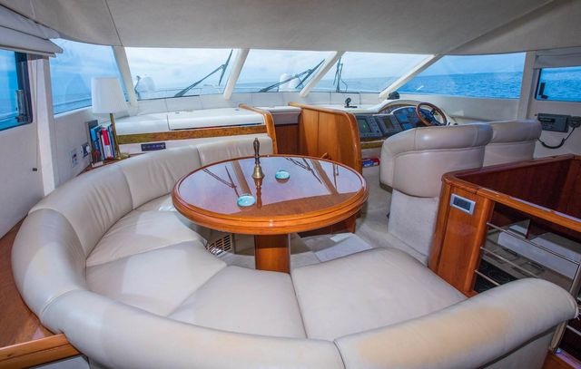 Luxury yacht interior: Elegant seating area with curved leather sofa, wooden table, and steering console on Elafiti Islands tour