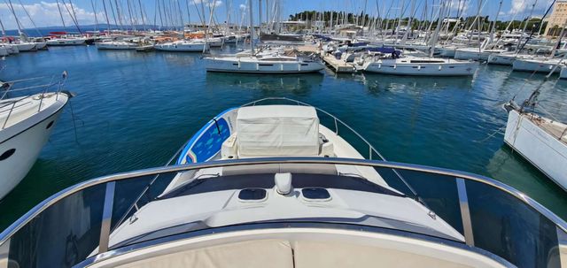 View from a motorboat in a vibrant Dubrovnik Frapa marina, packed with numerous sailing yachts and other vessels, under a clear blue sky.