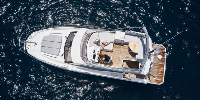 Aerial view of a luxury yacht from our fleet sailing in crystal-clear blue waters, featuring multiple decks, spacious lounging areas, and a sleek white exterior.