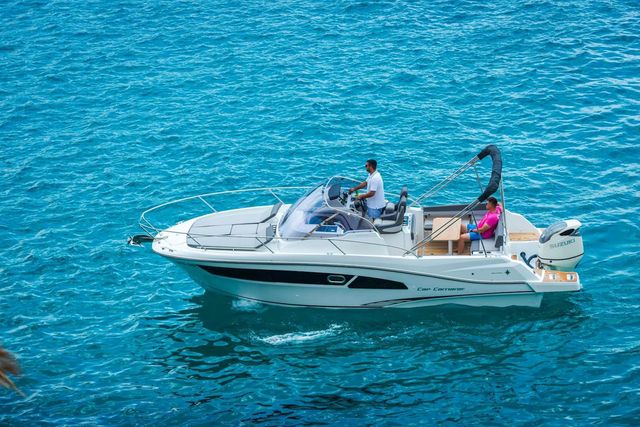 White Cap Camarat motorboat with Suzuki outboard engine cruising on crystal blue sea. Powerboat rental for summer vacation and coastal exploration.